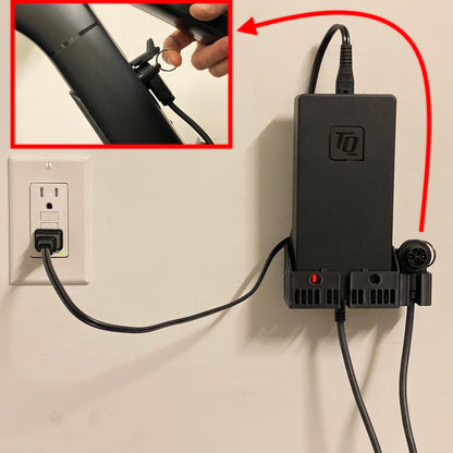A black wall mount bracket for a TQ HPR50 4A charger, with a cable wrapped around it and a ring pull connector attached to the bracket.